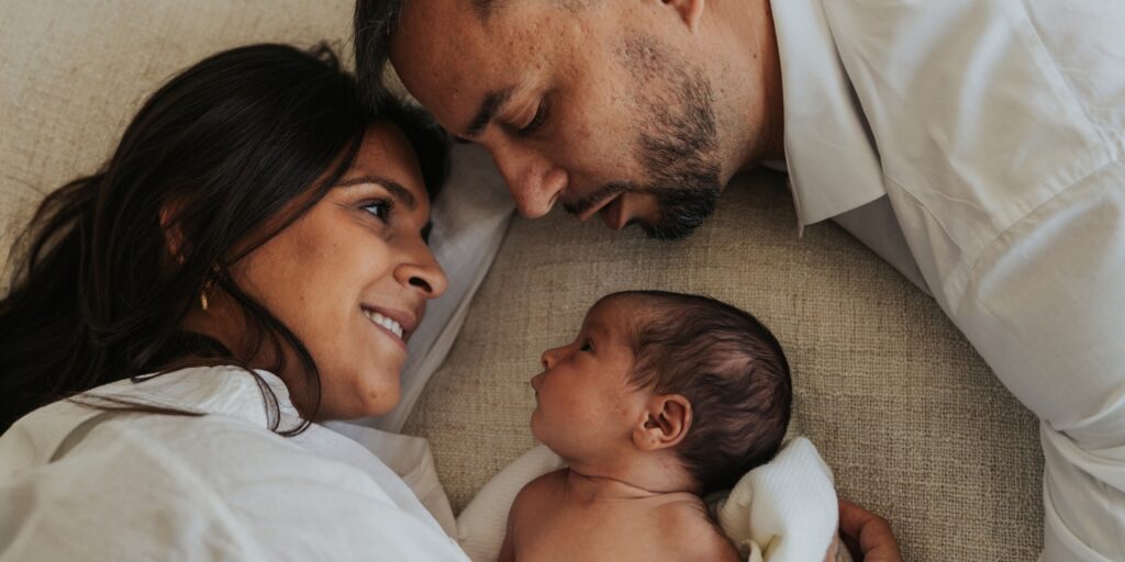 Padres con su bebé recién nacido durante una sesión newborn en casa